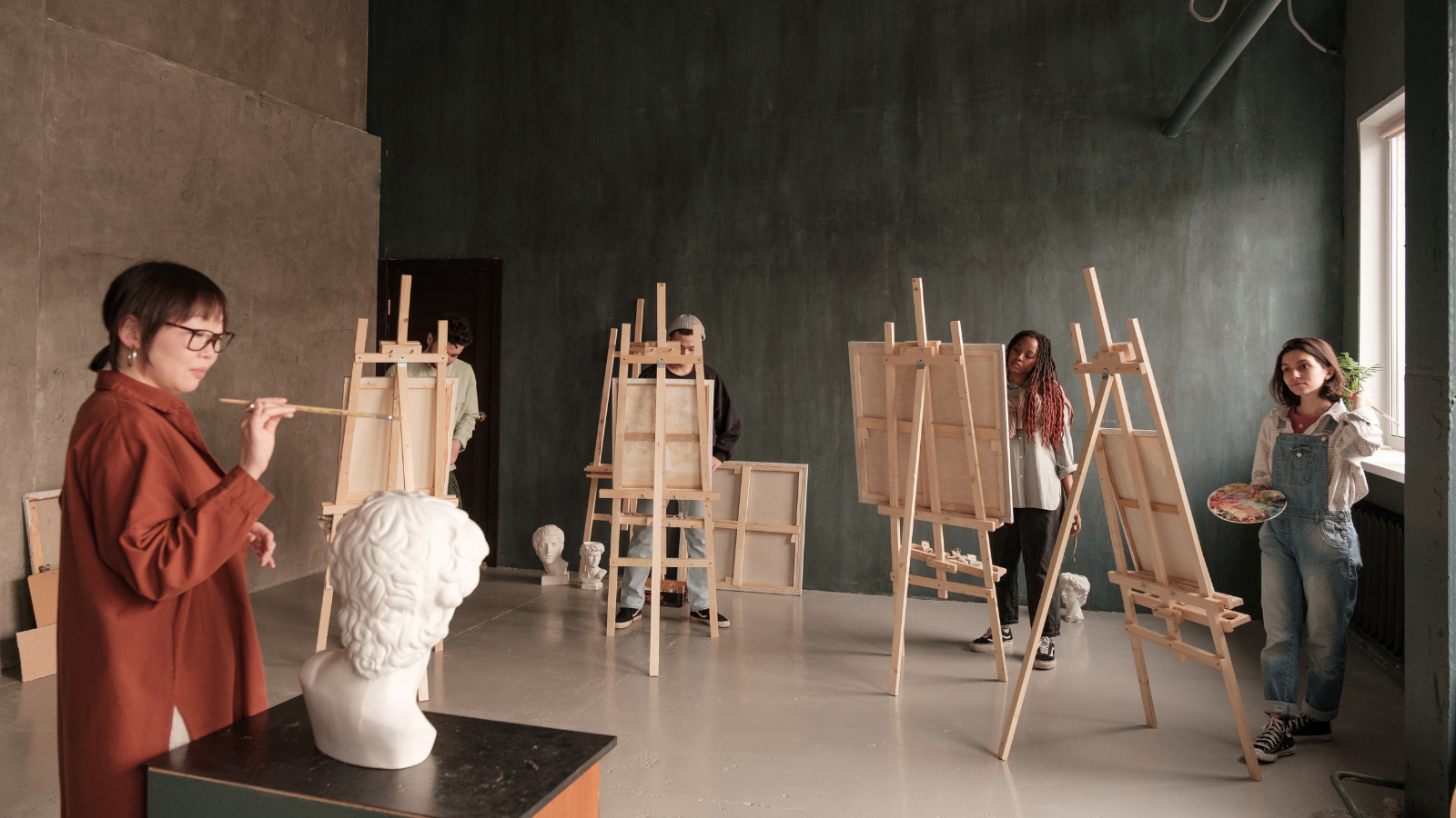 5 art students painting in a studio.