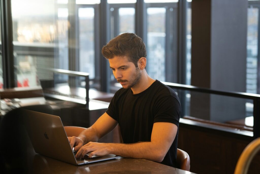 A bearded student researches student loans on his laptop.