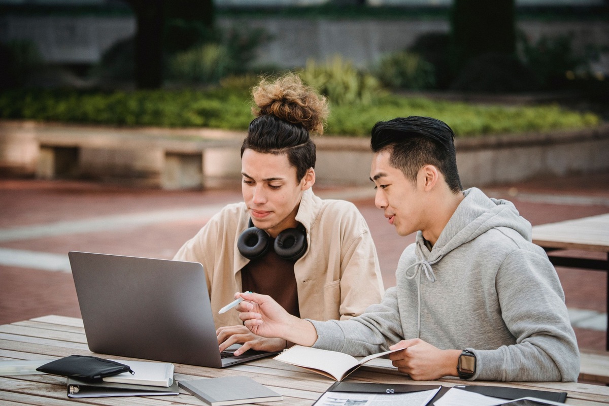 Two young male students study together on a bench.