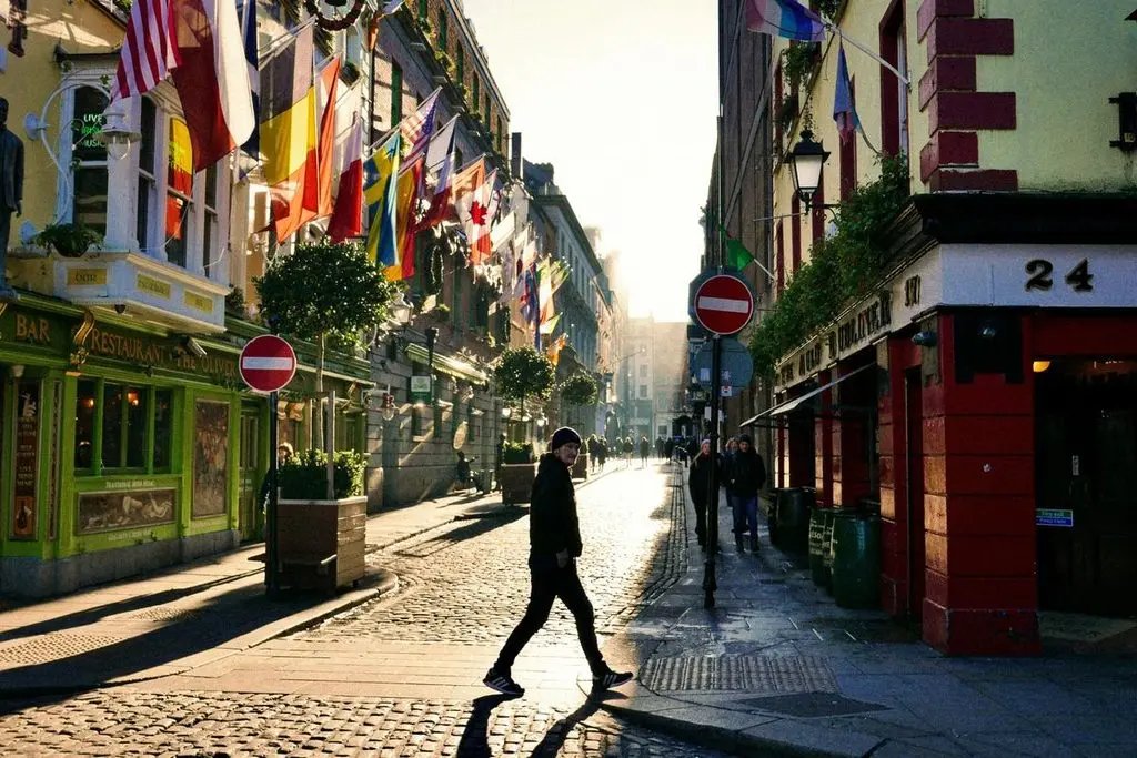 A man crosses the bright street in the Temple Bar area.